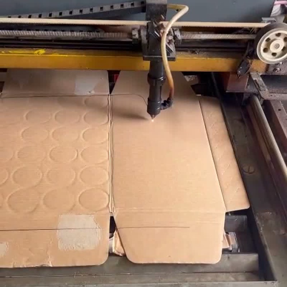 A CNC cutting head cutting a cardboard template from sheet stock