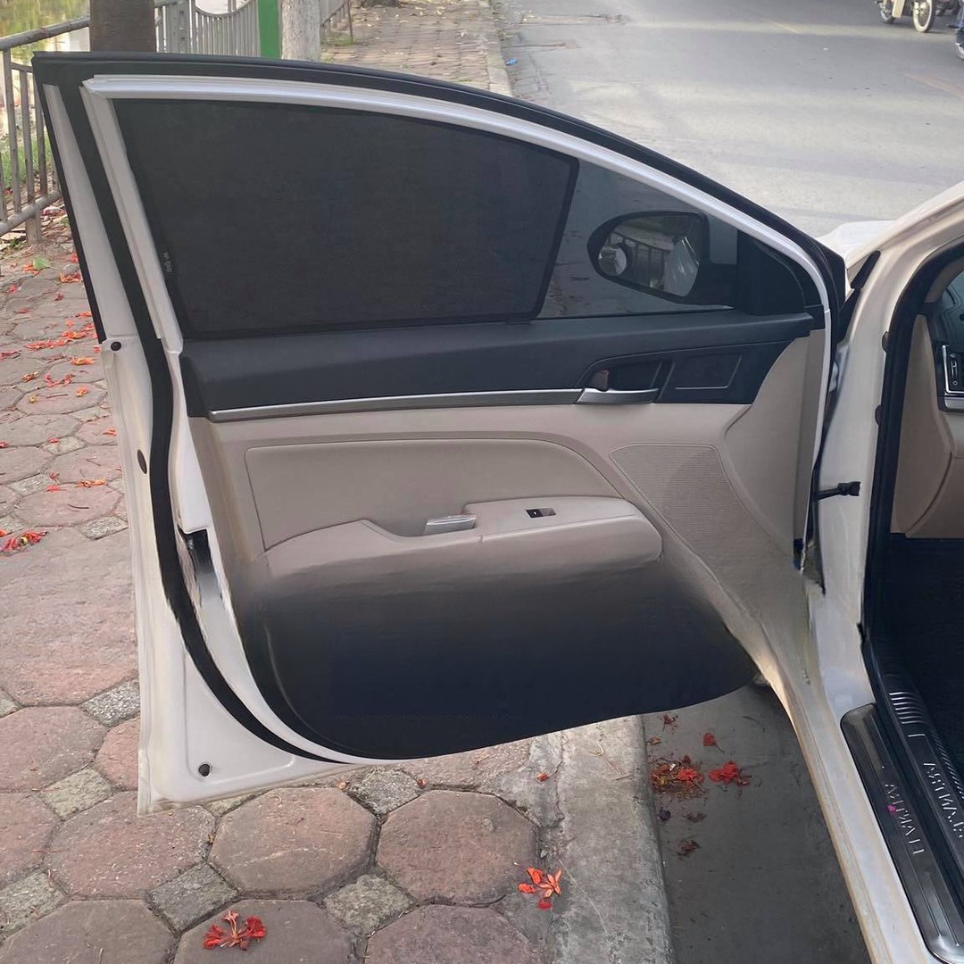 Open front door of a white Elantra sedan with a mesh shade fitted over the main door pane