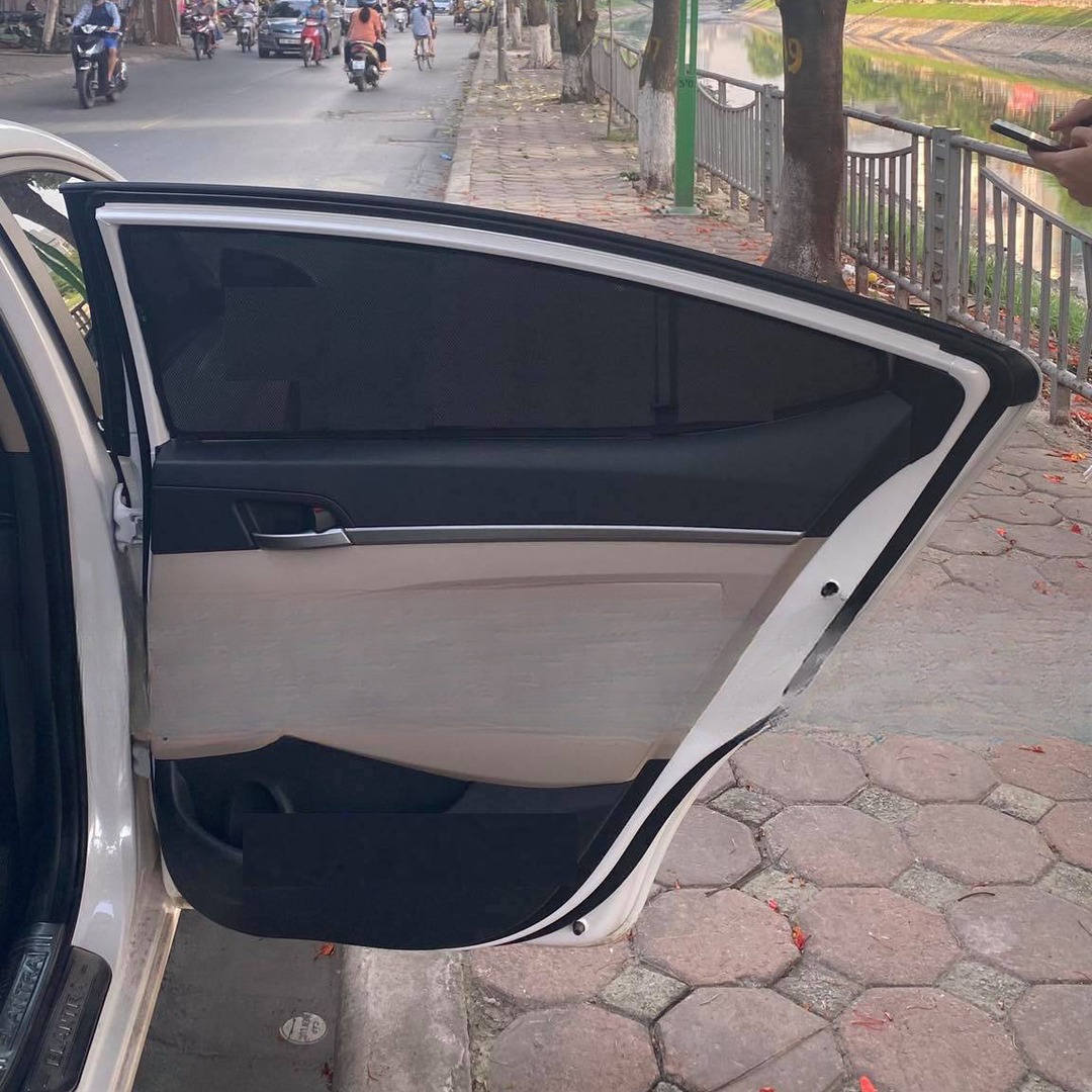 Open rear door of an Elantra sedan with a shade panel over the tapering rear door glass