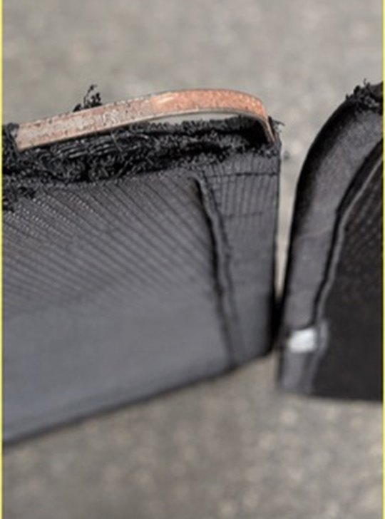 A corroded flat steel frame wire exposed at the fold of a shade