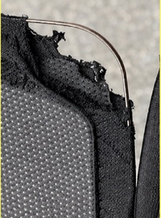 A flat steel frame wire that has worked through the fabric binding and torn the mesh